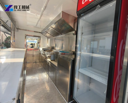Glass-front refrigerator beside the stainless work area inside a catering trailer