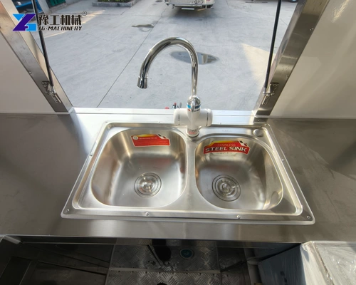 Two-bowl stainless sink with a curved tap inside a trailer worktop