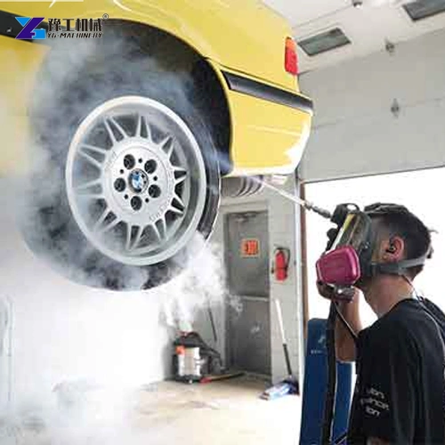 Operator cleaning beneath a raised vehicle with a dry ice nozzle